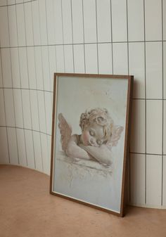 an angel painting sitting on top of a table next to a white tiled wall and floor