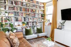 a living room filled with furniture and a flat screen tv mounted on a wall next to a window