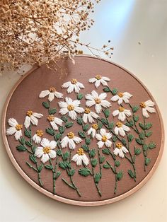 there is a embroidery pattern with daisies on the side and flowers in the middle