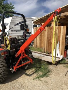 a red tractor parked next to a trailer with a ladder on it's back