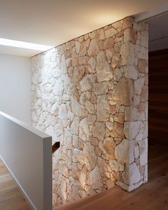 a stone wall in the corner of a room with wood flooring and white walls