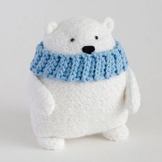 a white stuffed polar bear wearing a blue scarf and knitted neckwarmers