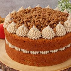 a cake with white frosting and crumbs is on a wooden platter