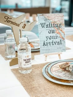 a table set up with water bottles, plates and napkins for guests to eat