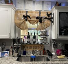 a kitchen with white cabinets and counter tops covered in burlocked valances