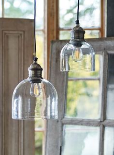 two clear glass pendant lights hanging from a window sill in front of a wooden door