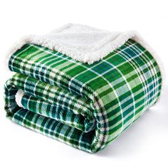 the green and white plaid blanket is folded on top of each other, with a sherp