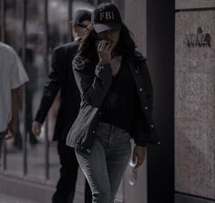 a woman is walking down the street talking on her cell phone while wearing a hat