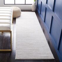 a white rug sitting on top of a hard wood floor next to a blue wall