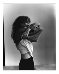 black and white photograph of a woman holding a sweater over her shoulder with both hands