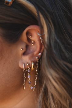 a close up of a person with ear piercings on their ears and wearing gold jewelry