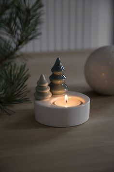 a lit candle sitting on top of a wooden table next to a pine cone ornament