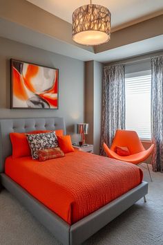 a bedroom with orange bedding and gray walls, an orange chair and painting on the wall