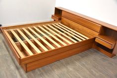 a wooden bed frame with drawers on the bottom and side panels open in a room