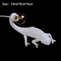 a white lizard figurine with a wine glass in it's mouth on a black background