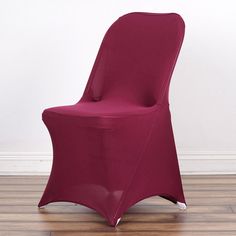 a red chair sitting on top of a hard wood floor next to a white wall