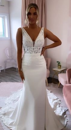 a woman in a white wedding dress posing for the camera with her hands on her hips