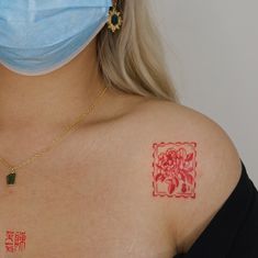 a woman wearing a face mask and tattoos on her chest with chinese writing in the upper corner