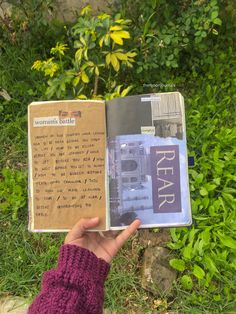 a person holding up a book in front of some bushes and trees with the words real written on it