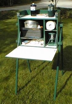 an outdoor table with pots and pans sitting on top of it in the grass