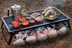 an outdoor grill with hamburgers and hot dogs cooking on it's side in the grass