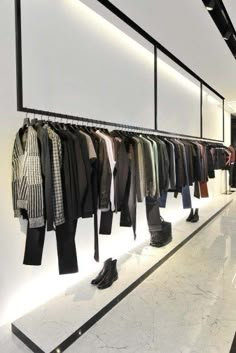 an empty clothing store with clothes hanging on the wall and shoes lined up in rows