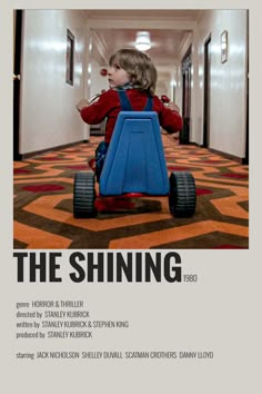 the shining movie poster with a little boy riding a toy car in an elevator hallway