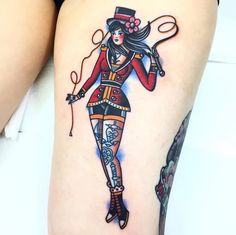 a woman with tattoos on her legs holding a string and scissors in one hand while wearing a top hat