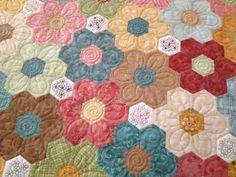 a close up of a quilt with many different colored flowers on the bottom and sides