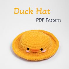 a crocheted yellow duck hat with black eyes and pink nose, on a white background