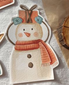 a snowman with a hat and scarf on it's head sitting next to other stickers