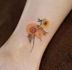 a sunflower tattoo on the foot of a woman's left ankle, with leaves and flowers