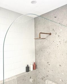 a bathroom with a glass shower head next to a white tiled bathtub and toilet