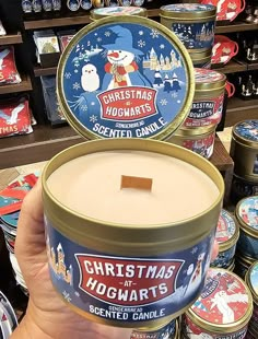 a hand holding a candle in front of many christmas themed candles on display at a store