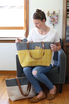 a woman sitting on a chair holding a yellow and gray bag