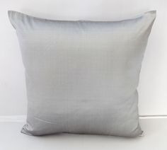 a gray pillow sitting on top of a white floor