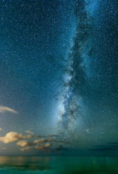 the night sky is filled with stars and bright green water, as well as clouds