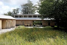 a house that is in the middle of some grass with trees and flowers around it