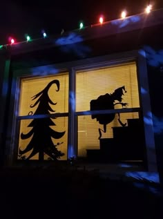 the silhouette of a horse is shown in front of a window with christmas lights on it