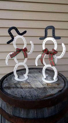 two snowmen made out of horseshoes sitting on top of a barrel