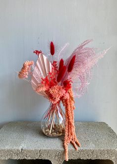 a vase filled with pink and red flowers sitting on top of a stone block wall