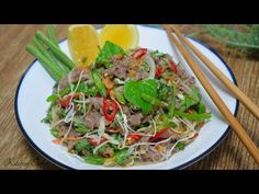 a white plate topped with meat and veggies next to chopsticks