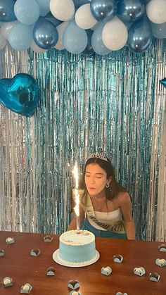 a woman sitting in front of a cake with a lit candle on top of it