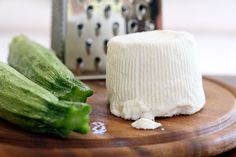 a wooden cutting board topped with cucumbers next to a cheese grater