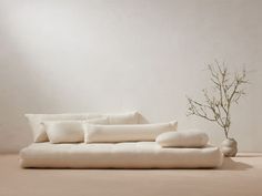 a white couch sitting next to a vase with a plant in it