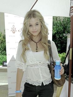 a young woman holding a water bottle in her right hand and standing under an umbrella