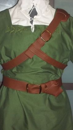 a green dress with brown leather straps and a white collared shirt on a mannequin's head