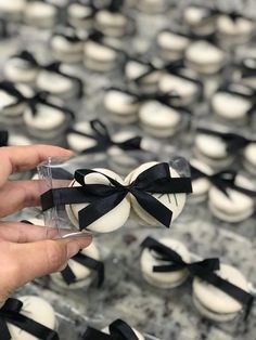 a person is holding some cupcakes with black bows on them in front of other cupcakes