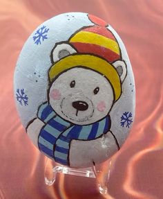 a painted rock with a bear wearing a hat and scarf on it's head