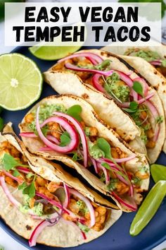 three tacos on a blue plate with limes and cilantro